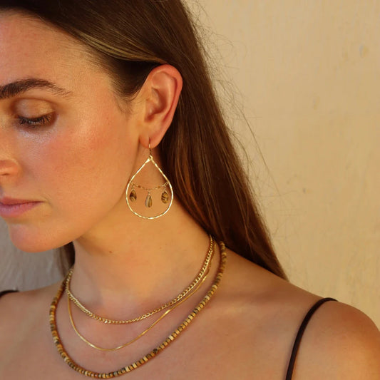 Gold dune earrings on models ear