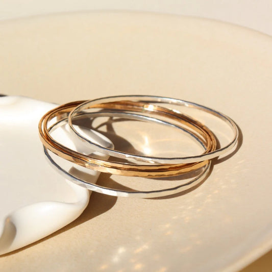 Hammered bangles stacked in gold and silver front and side view