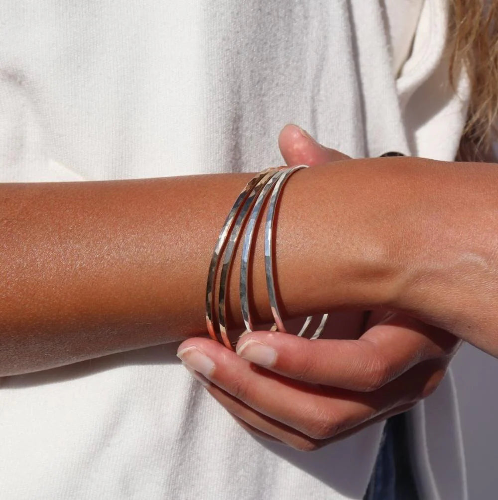 Hammered bangle in gold and silver on models wrist