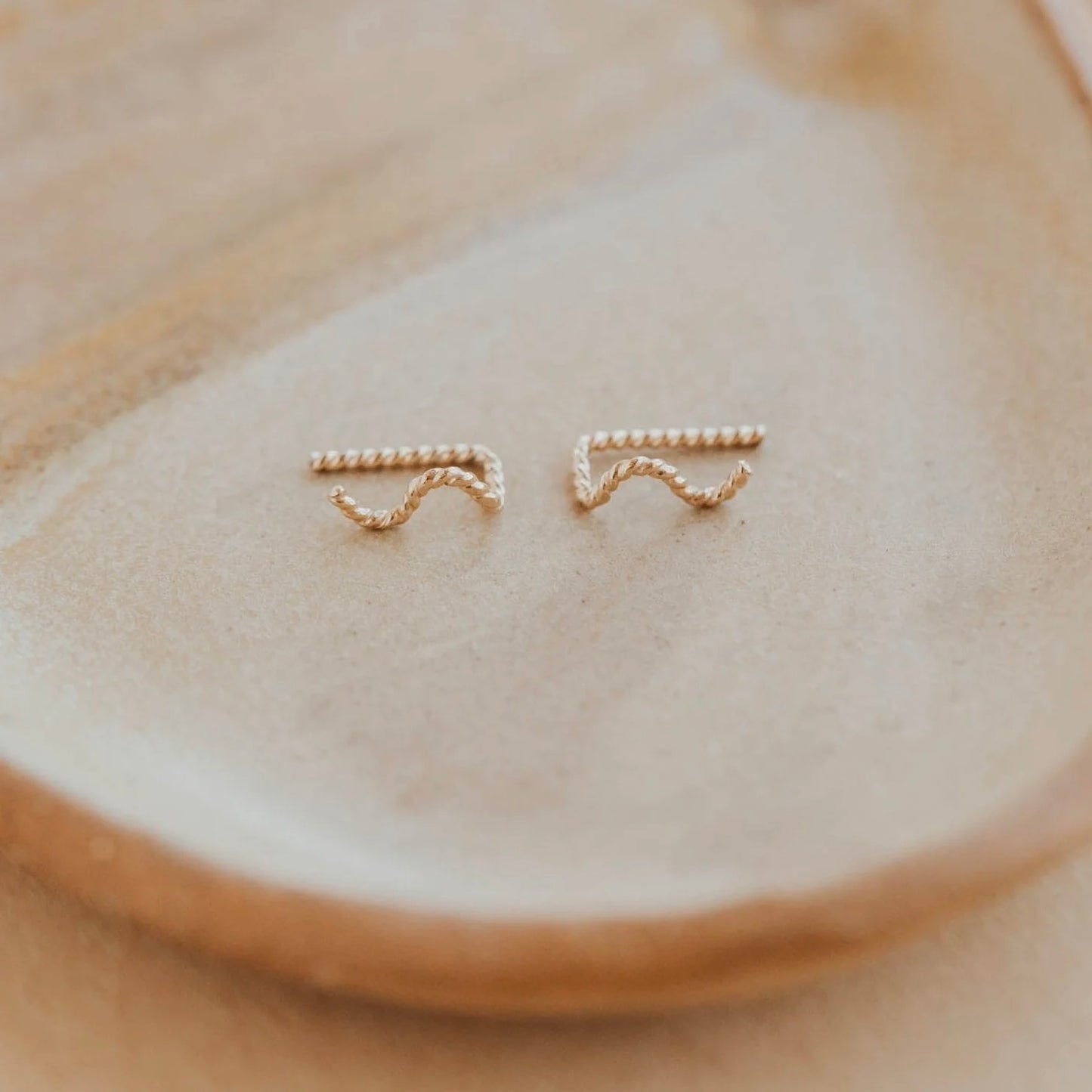 Gold serra ear climbers on display