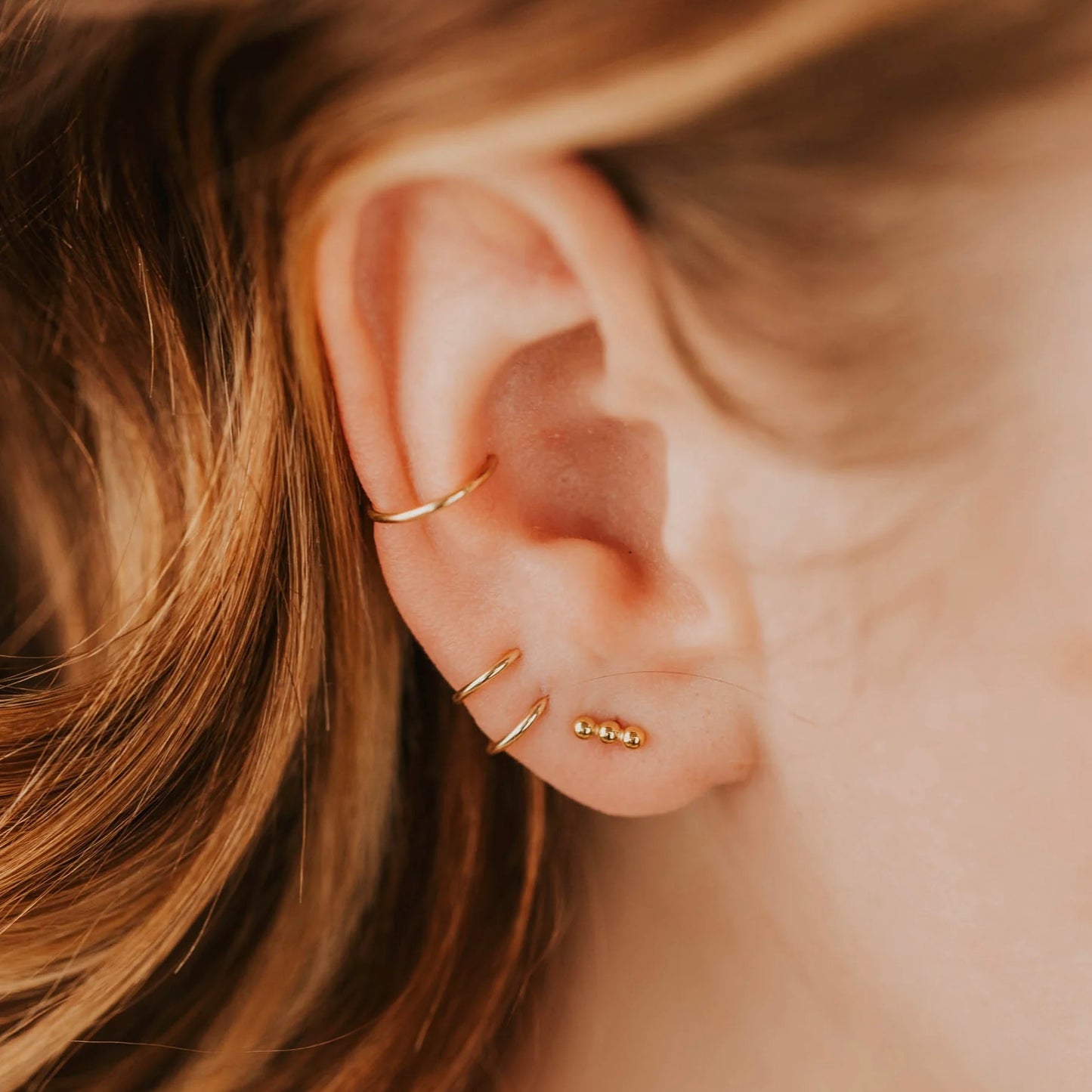 Gold triple dot studs on models ear stacked