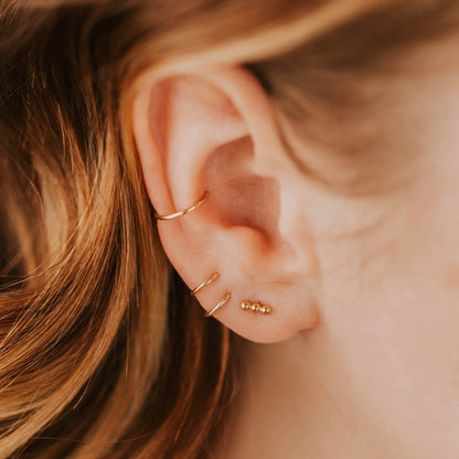 Gold triple dot studs on models ear stacked